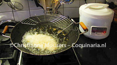 De gepaneerde schnitzel wordt gefrituurd in de wok